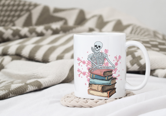 Taza de cerámica de esqueleto apoyado en libros con flores